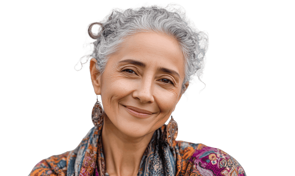 Smiling mature woman with silver-gray curly hair in loose updo, warm expression, large ornate earrings, and colorful patterned bohemian scarf and top